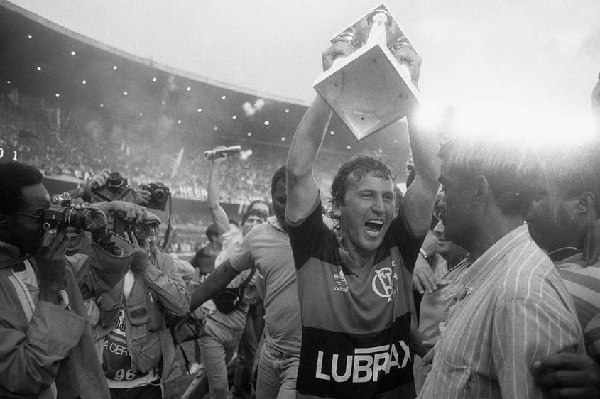 Fotografia real da Agência O Globo (publicada em Lance! e O Globo) registrando o momento exato em que o capitão Zico beija e ergue a taça da Copa União (Campeonato Brasileiro de 1987) no gramado chuvoso do Maracanã, após a vitória por 1 a 0 sobre o Internacional com gol de Bebeto diante de mais de 91 mil pagantes. (Fonte Oficial: Agência O Globo & Folha de S.Paulo (Acervo Oficial) · Agência O Globo & Acervo Folha de S.Paulo)