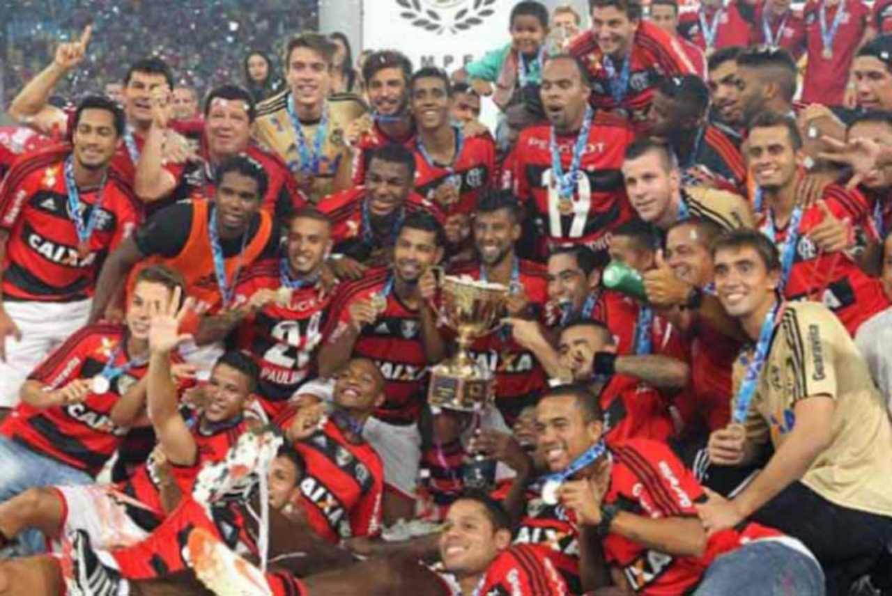 Fotografia real do capitão Leonardo Moura e elenco do Flamengo erguendo a taça de Campeão Carioca de 2014 no gramado do Maracanã (Foto: Julio Cesar Guimarães / Lancepress!), após o gol dramático de Márcio Araújo aos 46 minutos do segundo tempo contra o Vasco. (Fonte Oficial: Diário Lance! / Agência Lancepress! · Julio Cesar Guimarães / Agência Lancepress!)